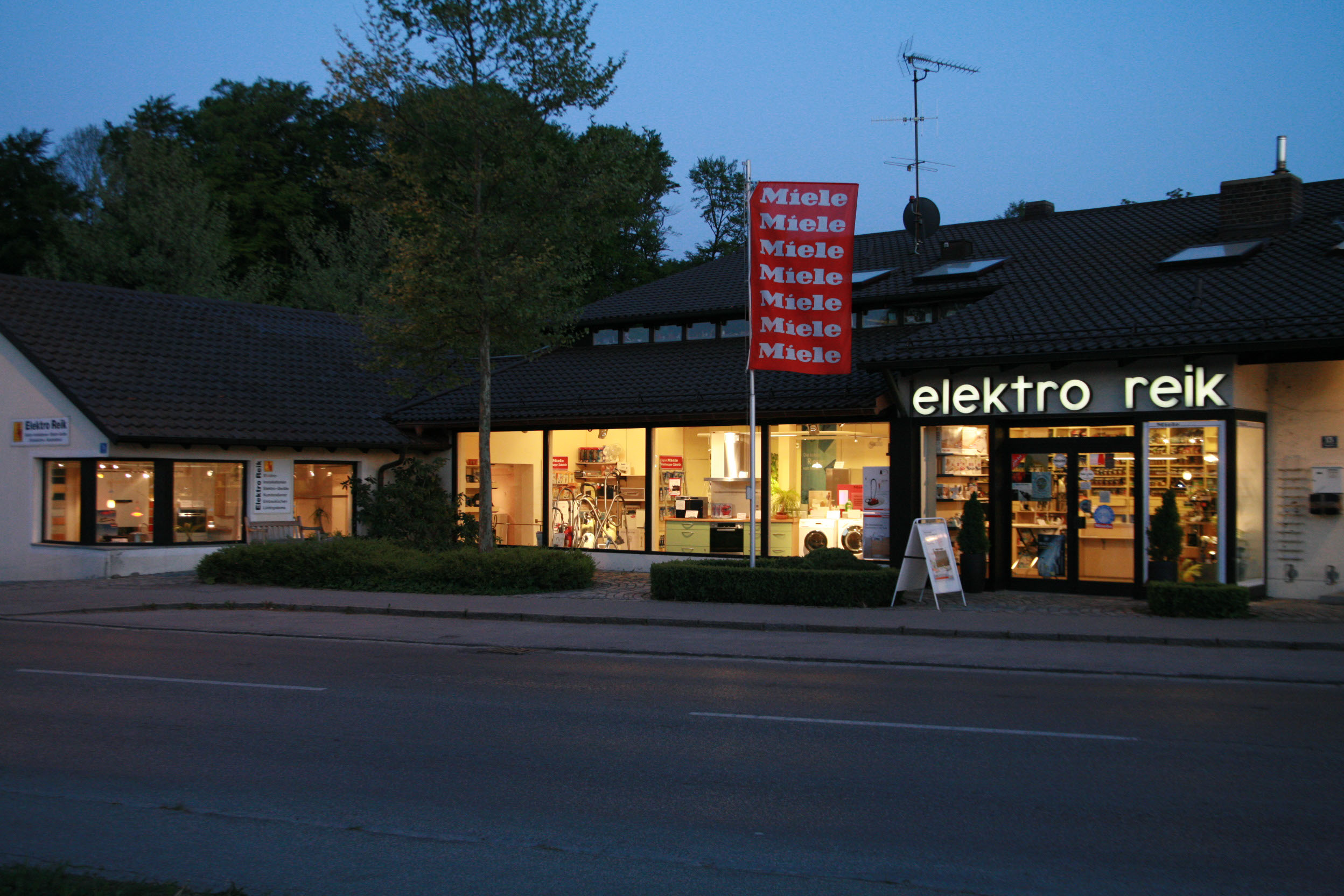 Das Ladengeschäft von Elektro Reik an der Hauptstraße in Weßling am Abend, die Schaufenster sind beleuchtet